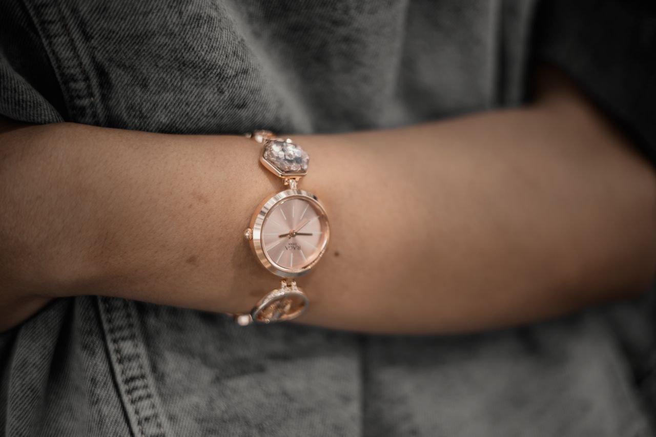 about-03 Close-up of a rose gold wristwatch worn by a woman, showcasing elegance and fashion.