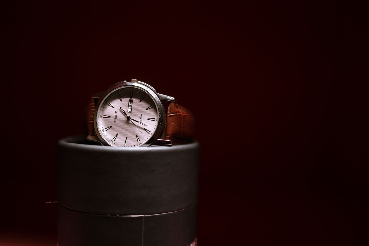 About Stylish Timex watch with a brown leather strap elegantly displayed on a cylindrical stand.